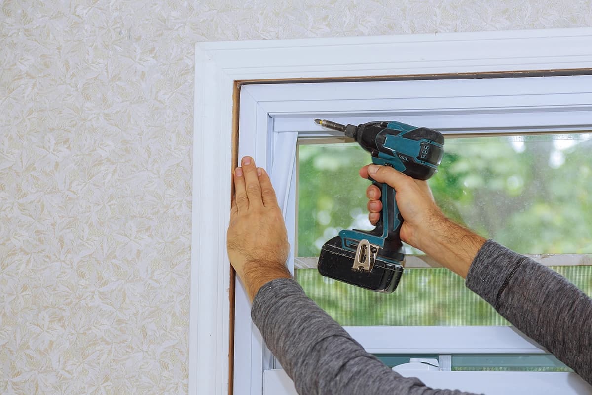 Worker installing a new plastic PVC window using a screwdriver
